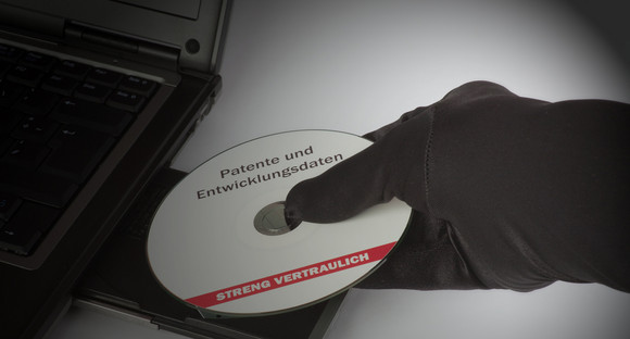 Behandschuhte Hand mit vertraulicher CD an einem Laptop. Quelle: Fotolia.