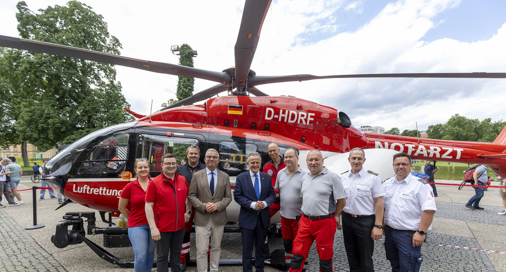 Innenminister Thomas Strobl und Stuttgarter Oberbürgermeister Dr. Frank Nopper umgeben von Personen vor einem Hubschrauber der Luftrettung. 