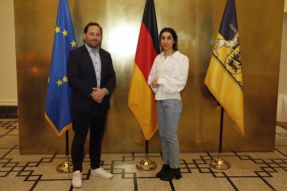 Gespräch Hassler empfängt Nadia Murad Staatssekretär Florian Hassler (links) und Friedensnobelpreisträgerin Nadia Murad (rechts) stehen in der Villa Reitzenstein in Stuttgart vor Fahnen.