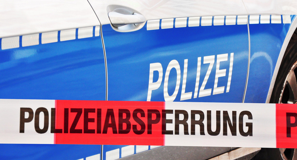 Polizeiabsperrung vor einem Streifenwagen.