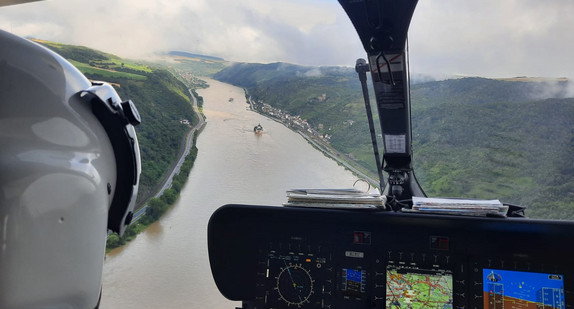 Blick aus dem Cockpit eines Hubschraubers auf einen überschwemmten Fluss.