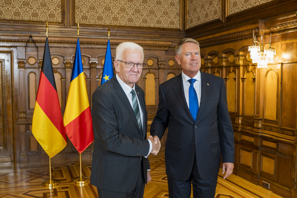 Europa Kretschmann auf Delegationsreise im Donauraum Ministerpräsident Winfried Kretschmann (links) und Rumäniens Staatspräsident Klaus Iohannis (rechts) stehen vor Fahnen und geben sich die Hand.