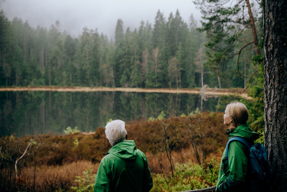 Ministerpräsident Winfried Kretschmann (links) und Umweltministerin Thekla Walker (rechts) blicken auf einen See.