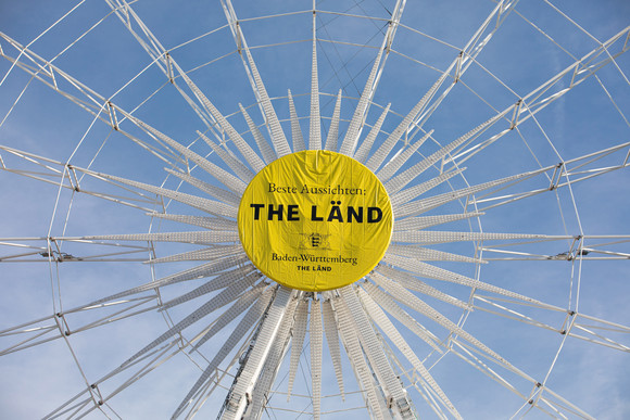 Imagekampagne Baden-Württemberg ist „THE LÄND“ Riesenrad auf dem Stuttgarter Schlossplatz mit der Aufschrift „Beste Aussichten: THE LÄND“ und dem Landeswappen