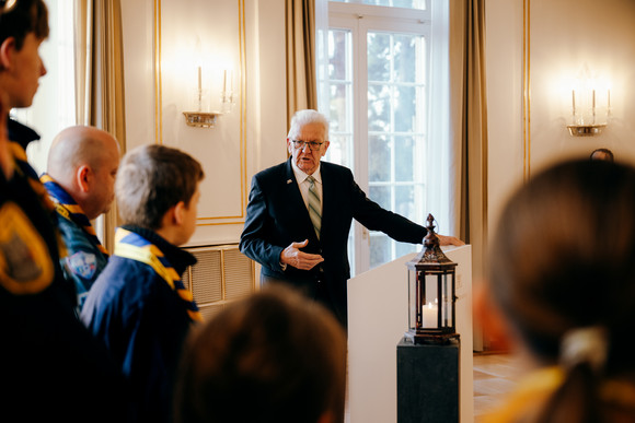 Ministerpräsident Winfried Kretschmann (rechts) mit Pfadfinderinnen und Pfadfindern bei der Übergabe des Friedenslichts