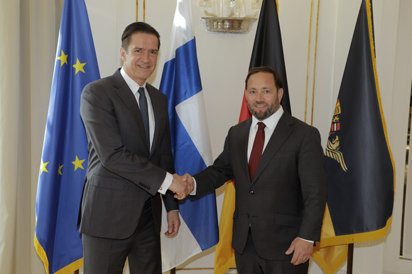 Antrittsbesuch Hassler empfängt finnischen Botschafter Staatssekretär Florian Hassler (rechts) und der finnische Botschafter Kai Jürgen Mikael Sauer (links) stehen vor Fahnen.