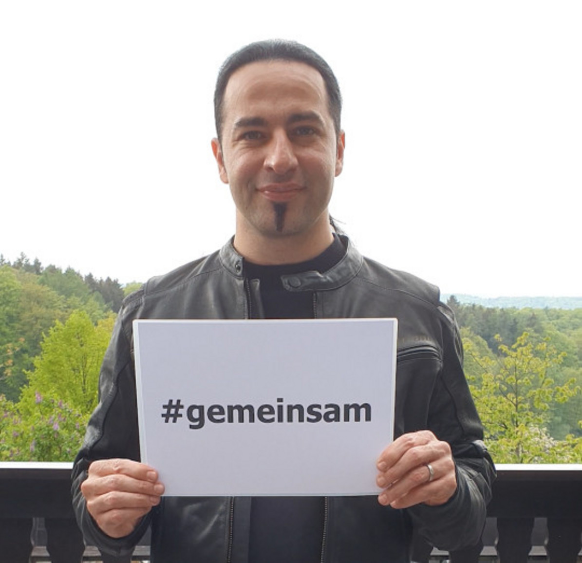 Bülent Ceylan hält ein weißes Blatt Papier in die Kamera mit der Aufschrift #gemeinsam