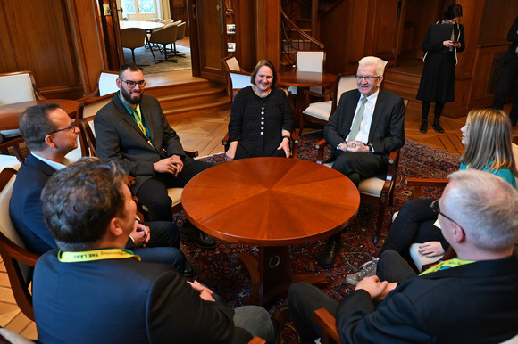 Schule BARCÄMP „Ein Schulfach für den Beruf“ Eine Gruppe von Personen mit Ministerpräsident Winfried Kretschmann und Kultusministerin Theresa Schopper sitzt an einem runden Tisch.