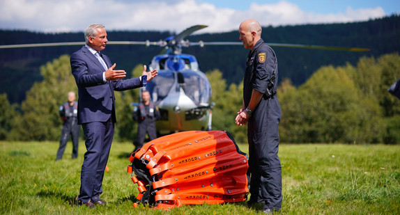 Innenminister Thomas Strobl lässt sich einen Außenlöschbehälter am Polizeihubschrauber zeigen.