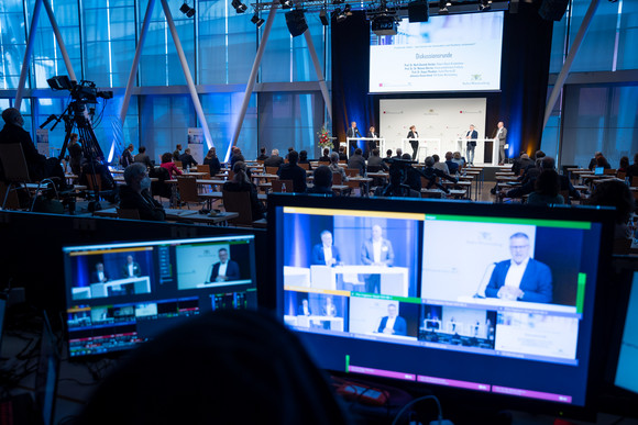 Gesundheit Dritte Jahresveranstaltung des Forums Gesundheitsstandort Im Vordergrund ein PC-Monitor, auf dem die Teilnehmenden einer Diskussionsrunde im Hintergrund auf der dritten Jahresveranstaltung des Forumgs Gesundheitsstandort Baden-Württemberg zu sehen sind.