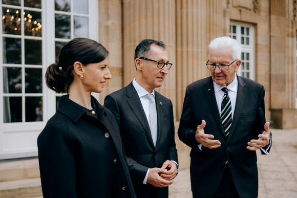 Ministerpräsident Cem Özdemir (Mitte) mit seinem Vorgänger Winfried Kretschmann (rechts) und Özdemirs Ehefrau Flavia Zaka (links) auf der Terrasse der Villa Reitzenstein