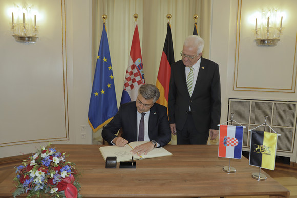Besuch Kretschmann empfängt kroatischen Premierminister Ministerpräsident Winfried Kretschmann (rechts, stehend) und der kroatische Premierminister Andrej Plenković (links, sitzend) beim Eintrag in das Gästebuch der Landesregierung