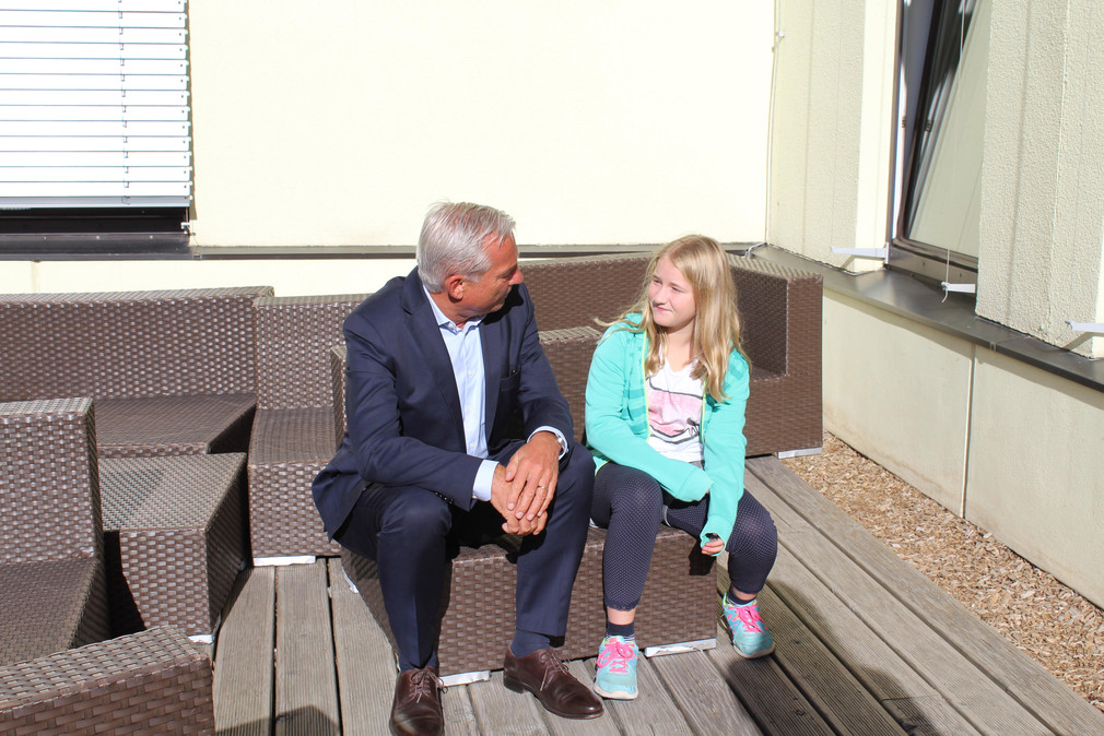 Minister Thomas Strobl und eine Schülerin unterhalten sich auf dem Pausenhof.