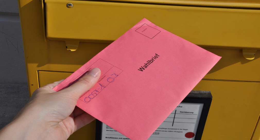 Wahlbrief wird in einen Postkasten geworfen. Quelle: Fotolia