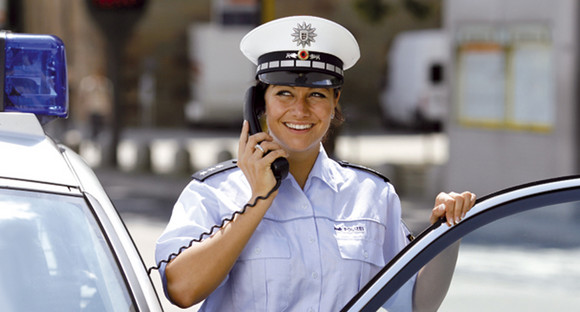Polizistin benutzt Funksprecher im Auto um eine Meldung zu machen.