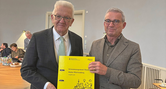 Innenminister Thomas Strobl übergibt das Krisenmanagement-Handbuch an Ministerpräsident Winfried Kretschmann