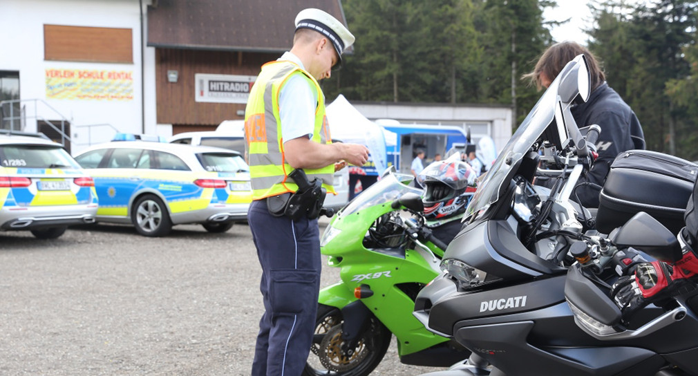 Ein Polizeibeamter kontrolliert einen Motorradfahrer.