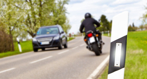 Motorradfahrer und Auto auf einer Landstraße. Quelle: Fotolia