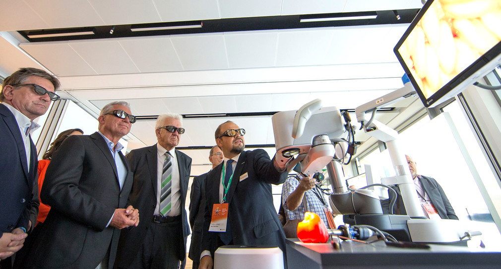 Gesundheitsminister Lucha, Digitalisierungsminister Strobl, Ministerpräsident Kretschmann und Aesculap Vorstand Dr. Schulz lassen sich das digitaleschirurgische Mikroskop des Unternehmens zeigen. 