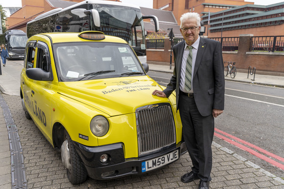 Auslandsreise Delegationsreise nach Schottland und England Ministerpräsident Winfried Kretschmann vor einem Londoner Taxi im Design der neuen „THE LÄND“-Kampagne