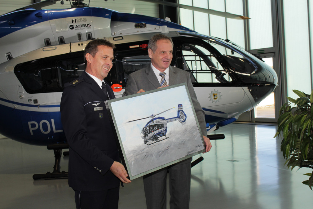 Innenminister Reinhold Gall überreicht dem Leiter der Hubschrauberstaffel, Polizeidirektor Michael Bantle, ein Gemälde des neuen Polizeihubschraubers